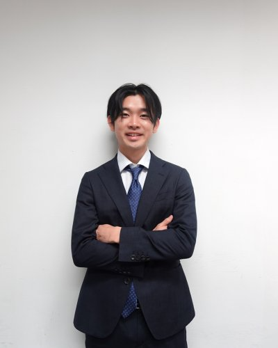 Male executive standing with arms crossed, wearing a blue suit